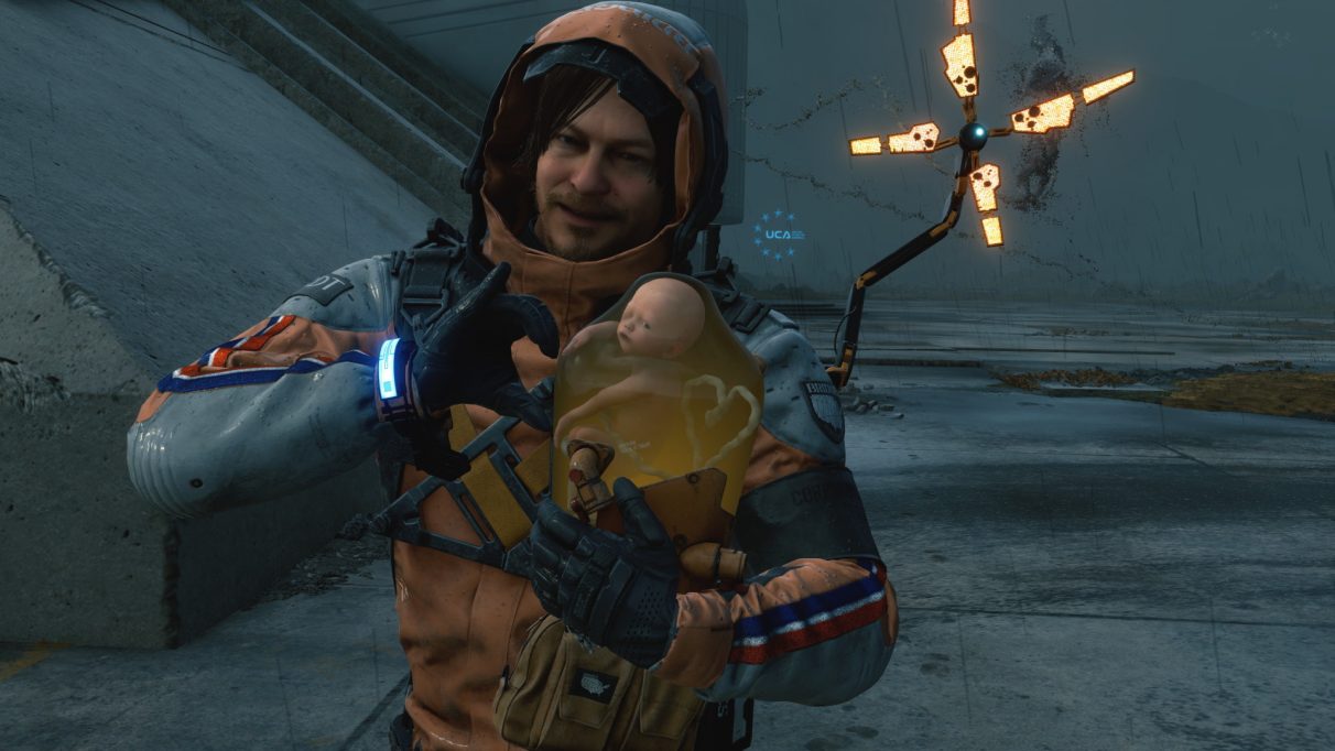 A screenshot of Death Stranding showing Sam Bridge making a heart shape with BB using the game's photo mode.