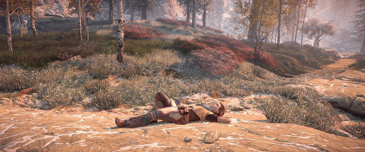 An ultrawide screenshot of Horizon Zero Dawn, with Aloy lying on down on a rock in a forest staring up at the sky.