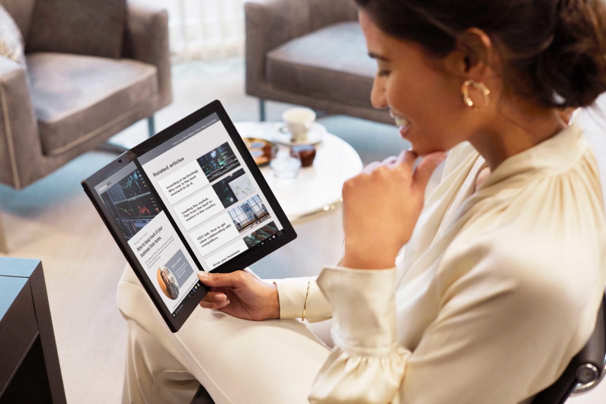 A woman enjoys business wine in a Lenovo ThinkPad X1 Fold 'lifestyle' photo.