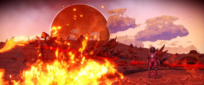 A screenshot of a big fire and a planet cresting the horizon while the player looks on in No Man's Sky.